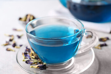 Glass cup of organic blue Anchan on light table, closeup. Herbal tea