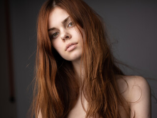 Portrait of beautiful woman on gray background bare shoulders close-up cropped view