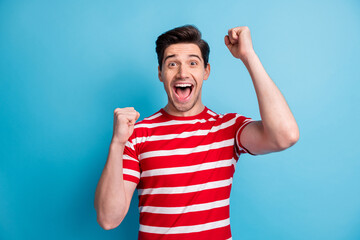 Photo of impressed cute sweet lucky funny guy dressed red clothes open mouth rising fists isolated blue color background