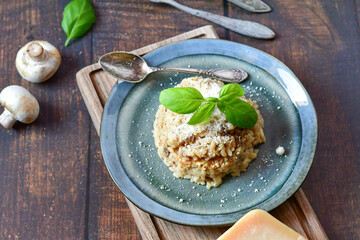 Italian  home made creamy   mushroom risotto with parmesan cheese and fresh basil on rustic background