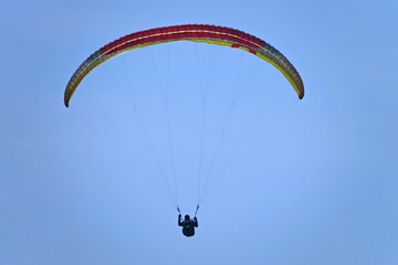 Paragliding. Extreme sport. Paraglider silhouette flying in the blue sky.