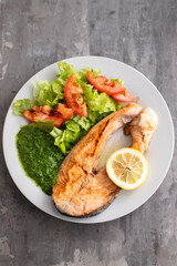 fried salmon with spinach and salad on white plate