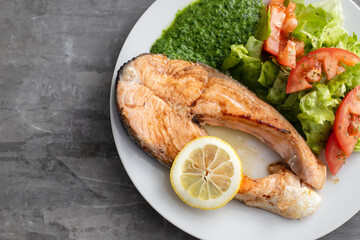 fried salmon with spinach and salad on white plate
