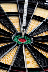 A closeup of dartboard with syringe in the red center, bulls eye. A concept for corona virus pandemic and mass vaccination  in the world. Stop the spread of covid 19