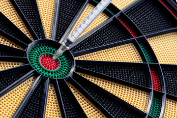 A closeup of dartboard with syringe in the red center, bulls eye. A concept for corona virus pandemic and mass vaccination  in the world. Stop the spread of covid 19