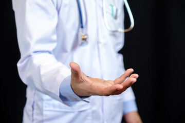 Portrait of confident young medical doctor on black background.