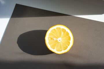 half of a whole lemon lies on a gray background. Sunlight feeds on the lemon