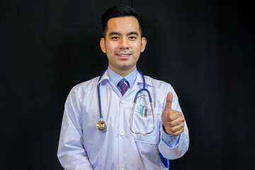 Portrait of confident young medical doctor on black background.
