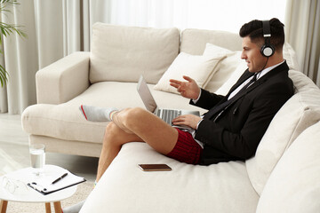 Businessman in jacket and underwear having videocall on laptop at home