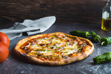 Homemade pizza with tomato, pepper, onion and meat surrounded by ingredients