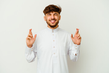 Young Moroccan man wearing a typical arab clothes isolated on white background crossing fingers for having luck