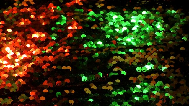 Abstract colorful texture of bright sequins. Glamor background with glittering multi-colored sequins on fabric, macro. Beautiful bright wallpaper with a pattern of round sequins.