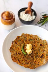 Radish or Mooli masala Paratha served on a white plate with butter cubes. Served with curd, pickle, and green chili. copy space. Muli ke parathe. Radish masala roti.