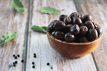 dried black olives with a stone in a wooden plate