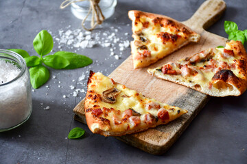 Slice of  home made italian  pizza carbonara on a wooden table