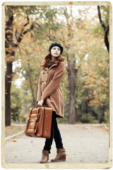 Obraz premium Redhead girl with suitcase at autumn outdoor