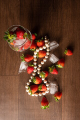 Strawberries, details of strawberries with ice cubes and a string of pearls on a table, black background, top view.