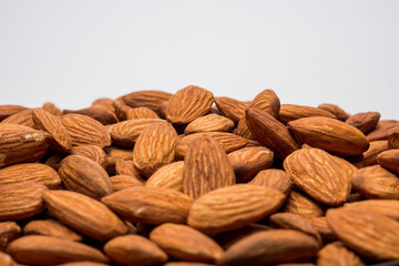 Whole almond nuts on the white background. Healthy vegetarian snack. Close-up photo. Space for your text.