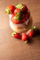 Strawberries, crystal bowl with strawberries and condensed milk on a table, black background, top view.