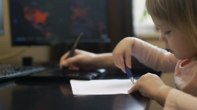 Online working during lockdown with a child, mommy and baby are drawing. Tender woman hand uses tab and a digial pen, kids hands writing on a paper. Cute interested blond girl by the computer table