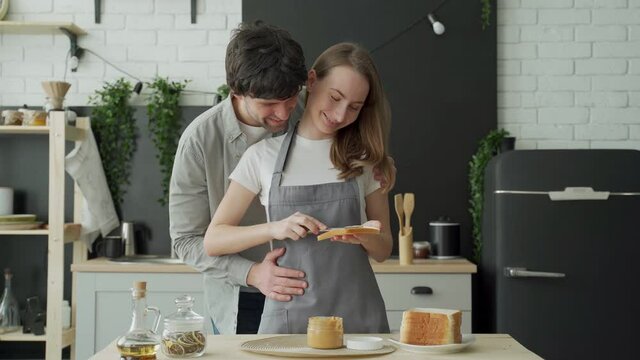 Young couple applying peanut butter on bread in the morning. Concept of happy home, family, food and health.