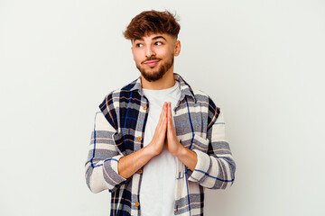 Young Moroccan man isolated on white background praying, showing devotion, religious person looking...