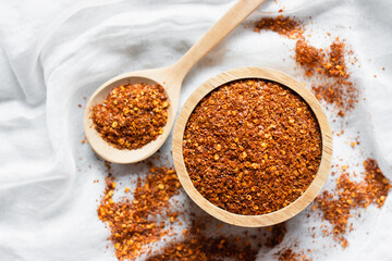The cayenne pepper in a wooden cup is placed on a white cloth.