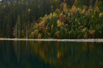 Beautiful lake view in the middle of mountains with green yellow orange red trees, reflected in water. Getaway vacation into natural surrounding. Mountain recreation. Low season in Bukovel ski resort