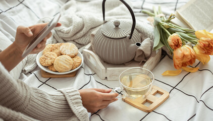 Still life with a cup of tea, a teapot, a bouquet and cookies in bed. Weekend and spring morning concept.