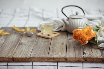 Spring home composition with a cup of tea, a teapot and a bouquet of flowers on a wooden surface.