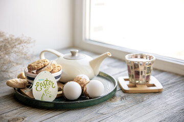 Easter composition with a cup of tea, teapot, cookies and Easter eggs.