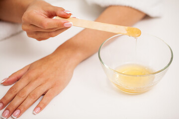 Obraz na płótnie Canvas Skin care, a woman applies wax to her hand to remove hair