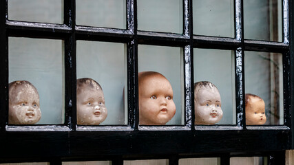 Collection of old doll heads in a window