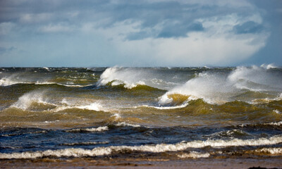 Storm clouds above the Baltic sea in winter. Dramatic sky, waves and water splashes. Dark seascape. Latvia.