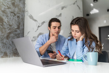 Unhappy American couple managing home accounts in kitchen, trying to save some money by cutting family expenses. Finances, bankruptcy, taxes, money, accounting and financial problems concept