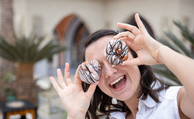 Close up of a funny girl posing with donuts in her hands.