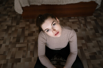 Fototapeta premium girl sitting at home on the floor, looking at the camera, portrait of a girl with freckles