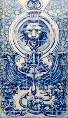 Portuguese traditional tiles Azulejos forming blue mosaic on a white background, which depicts lion holding a stand with two snakes, wings and flowers.