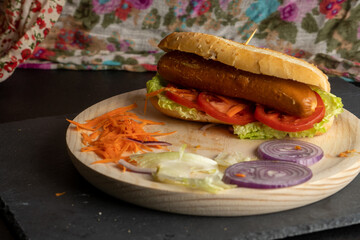 Vegetarian hot dog on a wooden tray with cut vegetables