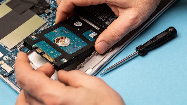 Close up laptop without cover inside disassembling in repair shop. Computer service engineer workplace repairing fixing broken components upgrade system, hard disk hdd solid state driver