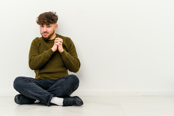 Young Moroccan man sitting on the floor isolated on white background scared and afraid.