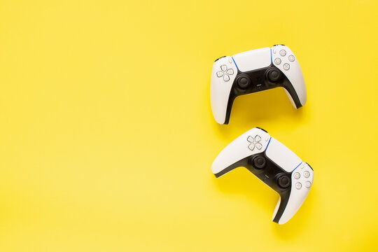 Ternopil, Ukraine - March 05, 2021: Two dualsense playstation 5 controllers on yellow background, gaming concept. Ps 5 gamepad	