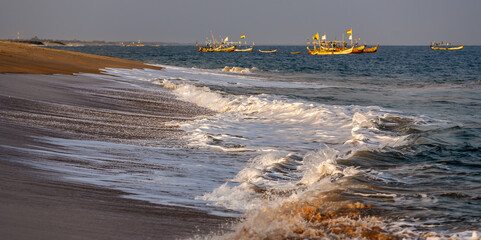 Sunset over Ghana's coast keta with foaming waves and fishing boats in the background
