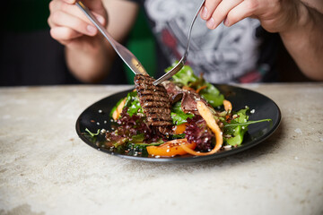 Man eating Steak Salad with Grilled Beef; arugula; carrot and seeds. Healthy food