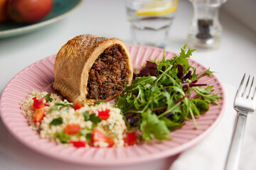 Vegan Meal On Plate With Savoury Roll Filled With Chickpea Lentil And Mushroom Next To Couscous And Salad