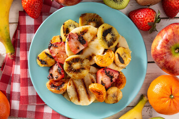 GRILLED FRUIT on a blue plate and white wooden table. Top view