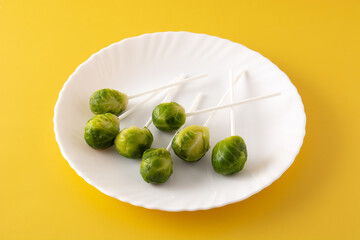 Set of brussel sprouts with lollipop sticks on yellow background