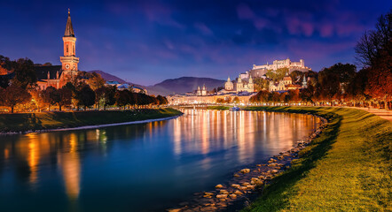 Fototapeta na wymiar Beautiful view of Festung Hohensalzburg and Castle Hohensalzburg during sunset with colorful sky with reflection in Salzach river in evening, Salzburg, Austria. Popular travel and historical center