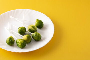 Set of brussel sprouts with lollipop sticks on yellow background