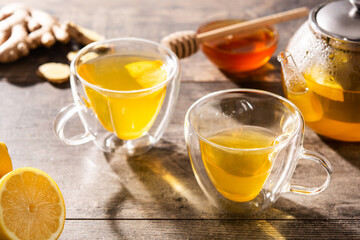 Ginger tea with lemon and honey in crystal glass on wooden table